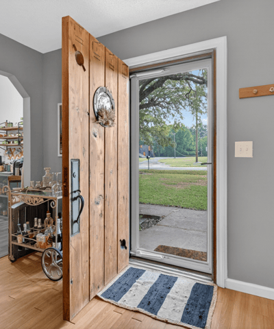Welcoming entryway featuring a solid wooden door, leading to an inviting, open living space with abundant natural light.