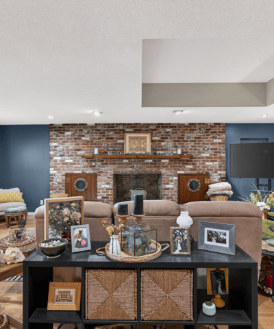 Spacious living area featuring exposed brick accents, ample natural light, and versatile entertainment options.