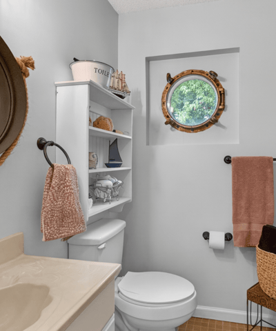 Bright bathroom featuring modern fixtures, a unique round window, and ample storage for convenience.