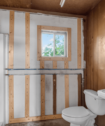 This unfinished bathroom features a shower area, sink, and window for natural light, ready for renovation.
