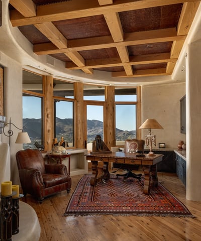 Command productivity and peace in this custom office retreat. Featuring built-in shelving, a rustic beamed ceiling, and a private patio framed by majestic mountain views, it blends inspiration with privacy in the heart of the home.