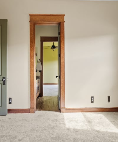 Bright bedroom with soft carpeting, wood-trimmed windows, and classic design elements. A comfortable space filled with natural light and timeless appeal.