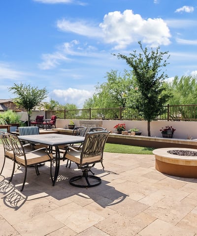 Enjoy cool evenings by the fire in this thoughtfully designed backyard oasis with lush greenery, raised planters, and a stylish built-in fire feature.