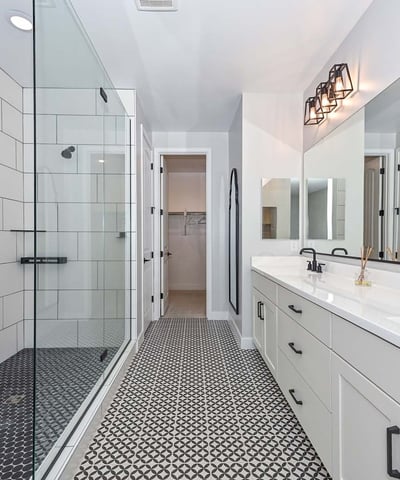 A luxurious retreat featuring geometric tile floors, walk-in glass shower, dual sinks, and upgraded matte black fixtures.