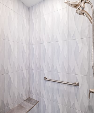 The shower s eye-catching tilework and sleek glass surround add elegance and modern flair to this beautifully updated bathroom.