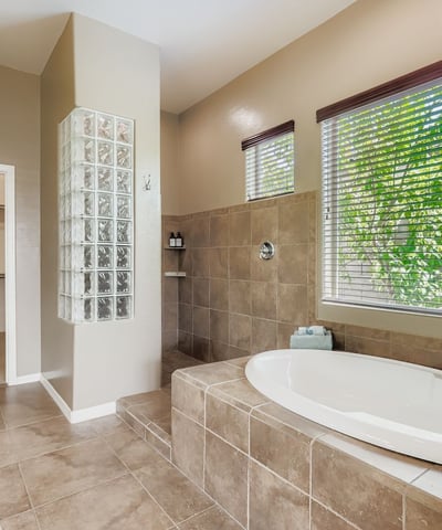 En-suite bath includes a soaking tub, walk-in shower, and oversized windows, creating a luxurious retreat at home.