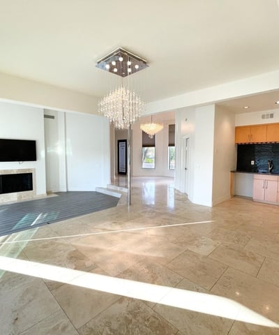 Open-plan living and dining area with glossy tile floors, recessed lighting, and a convenient wet bar for easy entertaining.