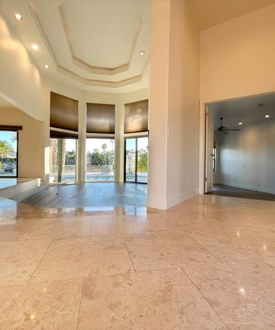Elegant entryway featuring high ceilings, marble floors, and crystal chandelier lighting that leads into the bright open living space.