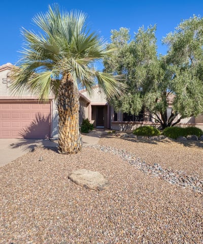 This charming front exterior showcases desert landscaping, mature trees, and timeless curb appeal an ideal first impression in Surprise.