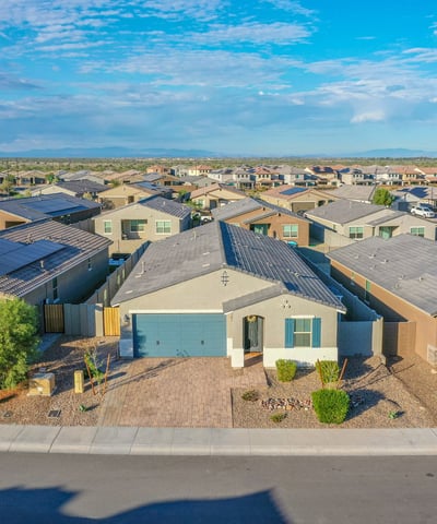 Drone-angle front view showcasing the home s attractive fa ade, paver driveway, and desert-friendly landscaping. Strong curb appeal in a desirable setting.