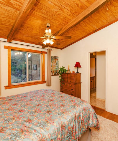 This restful primary bedroom showcases warm wood ceilings, soft textures, and scenic outdoor views. Its rustic charm reflects the essence of quiet living in Hackberry s desert landscape.