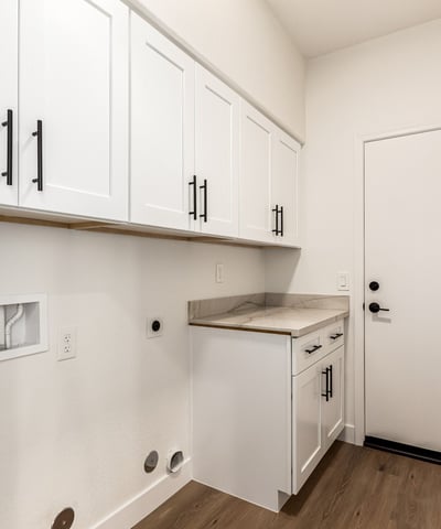 Well-designed Scottsdale laundry room featuring overhead cabinets, counter space, and washer/dryer hookups. The organized layout provides convenient storage and everyday functionality for household tasks.