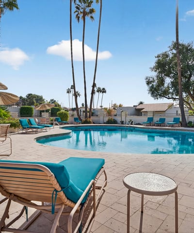 Beautifully maintained community pool surrounded by palm trees and lounge areas, offering a true resort-style atmosphere.