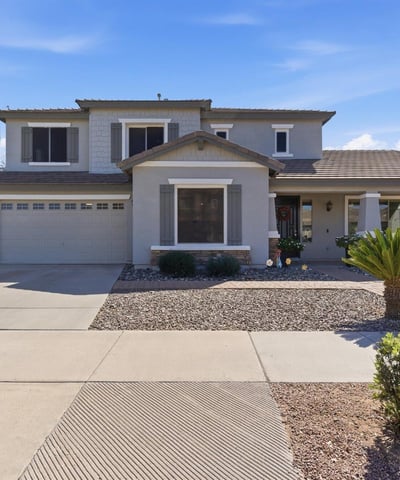 Attractive exterior of this Queen Creek property featuring a covered entry, desert landscaping, and attached garage in the popular Cortina community.