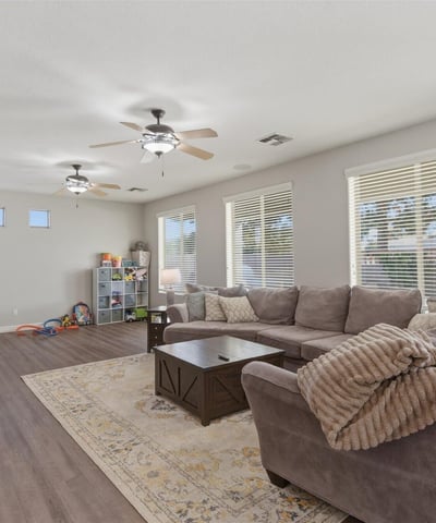 Large family room with multiple windows and modern flooring, offering plenty of space for relaxing, entertaining, or movie nights.