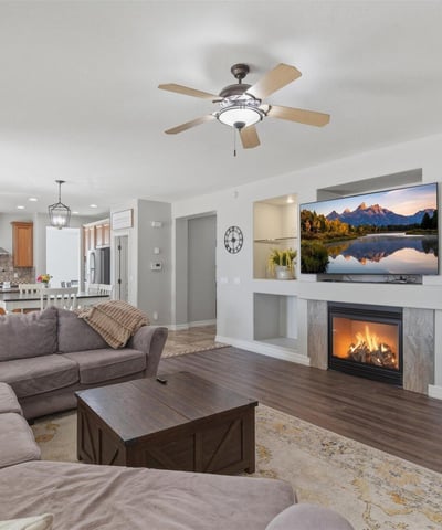 Stylish living area featuring a fireplace with decorative niches, ceiling fans, and durable wood-style flooring throughout the main living space.