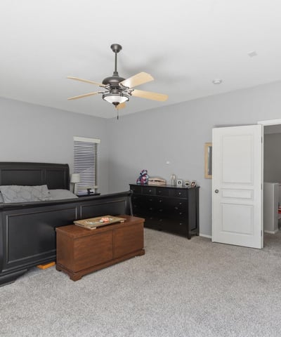 Generous primary suite featuring plush carpeting, large windows, ceiling fan, and ample space for bedroom furniture, creating a peaceful retreat in this Queen Creek property.