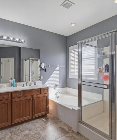 Primary bathroom with dual sinks, wood cabinetry, and bright lighting, providing a functional and stylish space for daily routines.