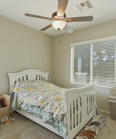 Comfortable secondary bedroom with plush carpet, ceiling fan, and large windows that bring in natural light, creating a welcoming space for guests or family.