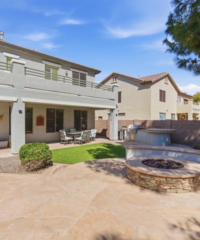 Backyard entertaining area featuring a built-in fire pit, spacious patio, and landscaped yard with pool views perfect for gatherings.