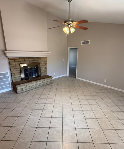 Comfortable living room featuring tile flooring, neutral colors, vaulted ceilings, and a stone fireplace centerpiece. This Glendale home provides a cozy environment for relaxing evenings.