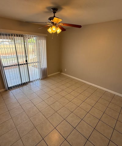 Generous bedroom layout with ceiling fan, tile flooring, and closet access. The neutral palette creates a comfortable and versatile living space.