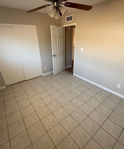 Bedroom with sliding closet doors, tile flooring, and ceiling fan lighting. Neutral finishes provide a clean and versatile interior space.