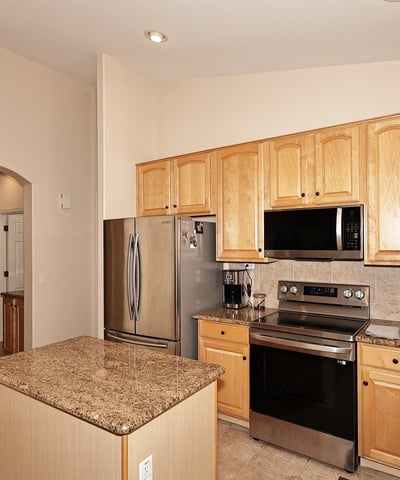 Kitchen with granite island, stainless appliances, and warm wood cabinetry. This Phoenix home provides functional prep space and a welcoming cooking area.