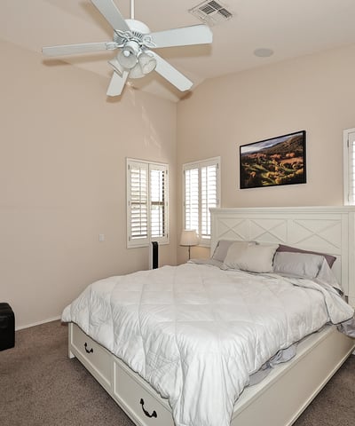 Comfortable primary suite with large windows, soft carpet, and open layout. This Phoenix home provides a relaxing retreat with functional space and natural light.