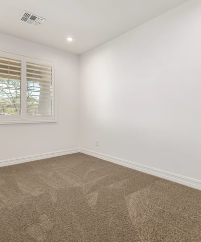 Well-lit bedroom with neutral tones and plush carpet, perfect for guests, family, or a flexible living space.