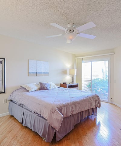 Primary bedroom with natural light, ceiling fan, and sliding door access to the backyard, offering a relaxing private retreat.