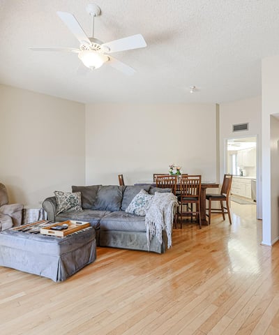 Open living and dining area with hardwood flooring, ceiling fan, and easy flow into the kitchen, ideal for gatherings and daily living.