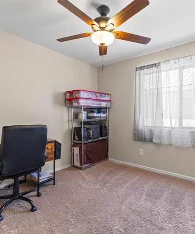 Bright bedroom with carpet flooring, large window, and ceiling fan. A comfortable space suited for multiple uses