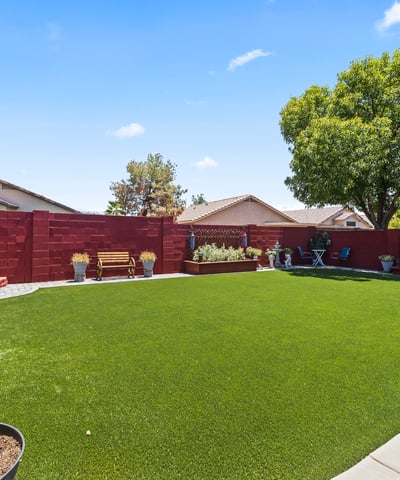 Spacious yard with artificial turf, raised garden beds, and decorative landscaping. Ideal for gardening and outdoor enjoyment.