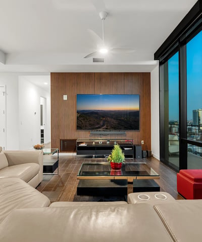 Stylish great room with expansive glass walls, modern finishes, and sweeping Phoenix skyline views, creating a bright and inviting living space.