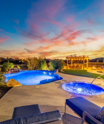 Stunning backyard oasis with pool, spa, pergola, and desert landscaping, showcasing Scottsdale luxury outdoor living during golden hour.