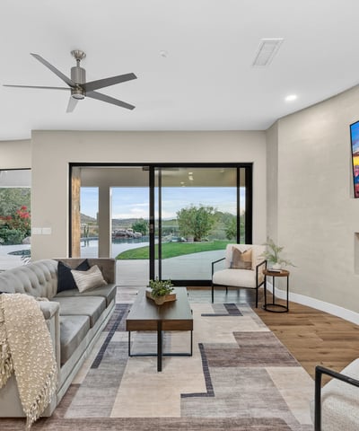 Open-concept living room with sleek fireplace, wood floors, and sliding doors leading to the backyard, showcasing Scottsdale indoor-outdoor design.