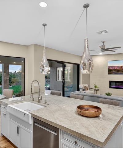 Spacious kitchen island with farmhouse sink and pendant lighting, overlooking the Scottsdale backyard with pool and lush landscaping.