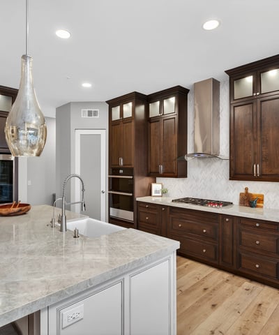 Beautifully upgraded kitchen featuring dark wood cabinetry, quartz surfaces, stainless appliances, and modern backsplash in this Scottsdale home.