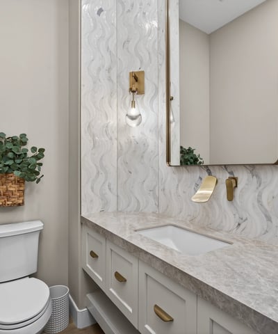 Elegant powder room with updated vanity, quartz countertop, decorative backsplash, and modern lighting in this Scottsdale residence.