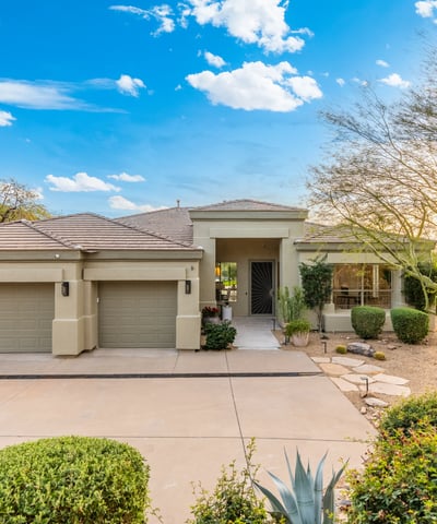 Scottsdale home exterior featuring desert landscaping, three-car garage, and welcoming entry for strong curb appeal.