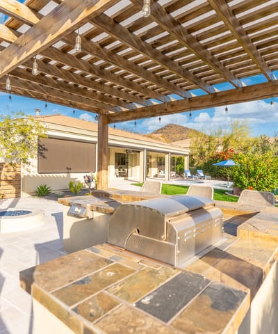 Scottsdale outdoor entertaining area with pergola, kitchen, and seating, offering a stylish and functional backyard retreat.