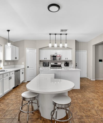 Functional kitchen with breakfast bar, white cabinets, and modern appliances. Seamless connection to living areas enhances flow in this Casa Grande home.
