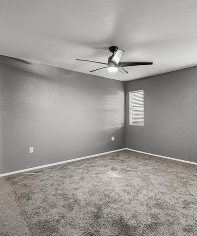 Spacious bedroom with soft carpet, ceiling fan, and neutral tones. This Sun City home provides a relaxing retreat with move-in ready comfort.