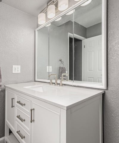 Well-lit vanity area with updated cabinetry and modern mirror. This Sun City home features upgraded bathrooms and functional design.