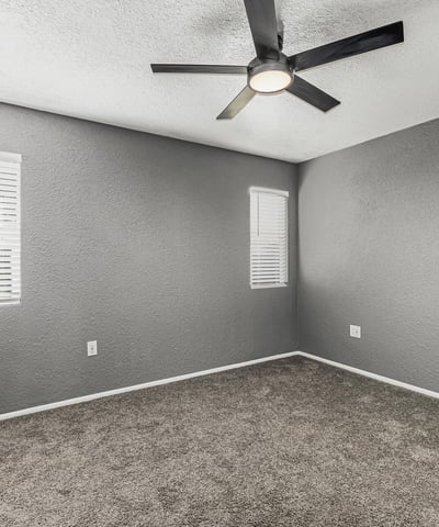 Comfortable bedroom featuring soft carpet, ceiling fan, and bright windows. This Sun City home offers updated finishes and inviting living spaces.