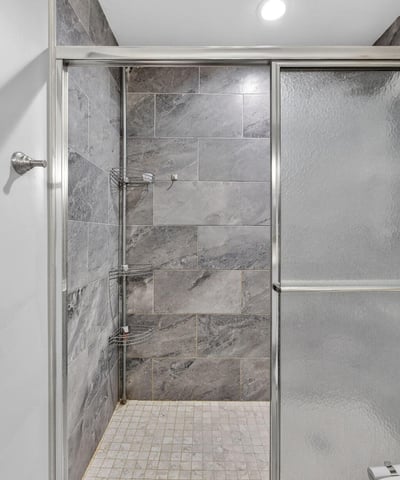 Detailed view of tiled walk-in shower with sleek finishes and glass doors, showcasing recent bathroom upgrades.