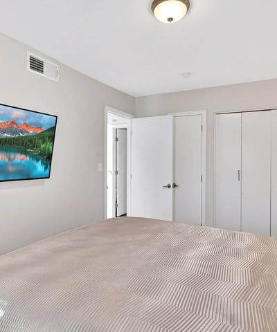 Scottsdale bedroom with wall-mounted TV, neutral tones, and practical layout, offering a comfortable and functional retreat.