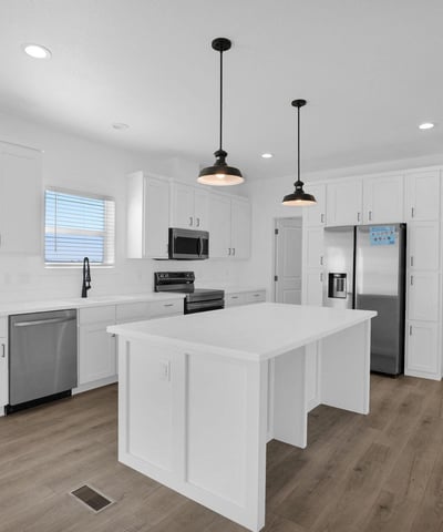 Modern kitchen with an oversized island, abundant cabinet storage, stainless steel appliances, and a walkthrough pantry. The clean design and generous workspace make meal preparation and entertaining effortless.