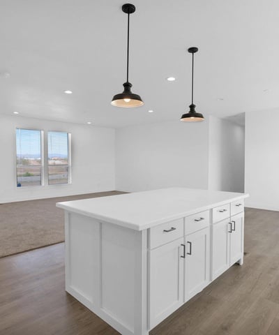 Stunning kitchen featuring an oversized center island, shaker cabinetry, modern lighting, and open sightlines to the living area. This impressive space is ideal for cooking, dining, and gathering with guests.